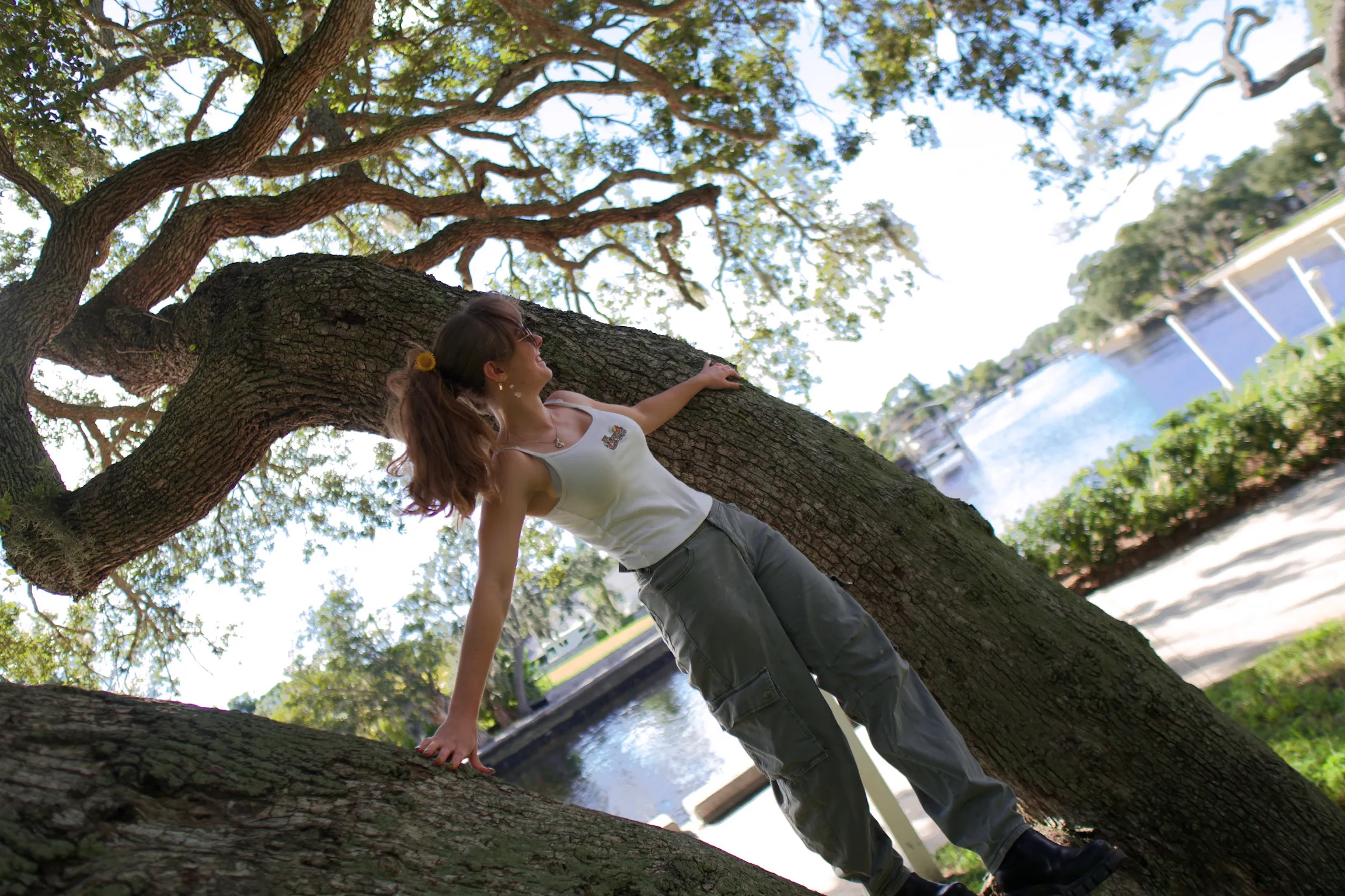 A woman braced against a leaning oak trunk with her hair swinging