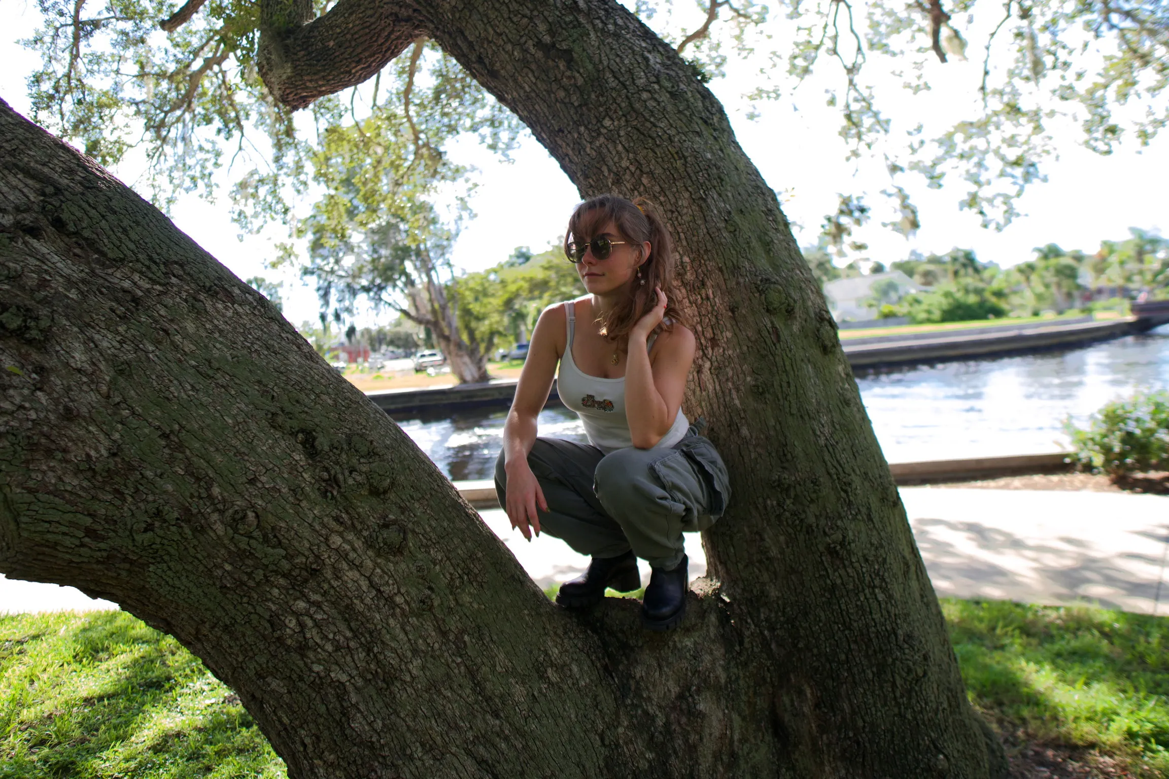 A woman crouched at the base of an oak, looking at the camera