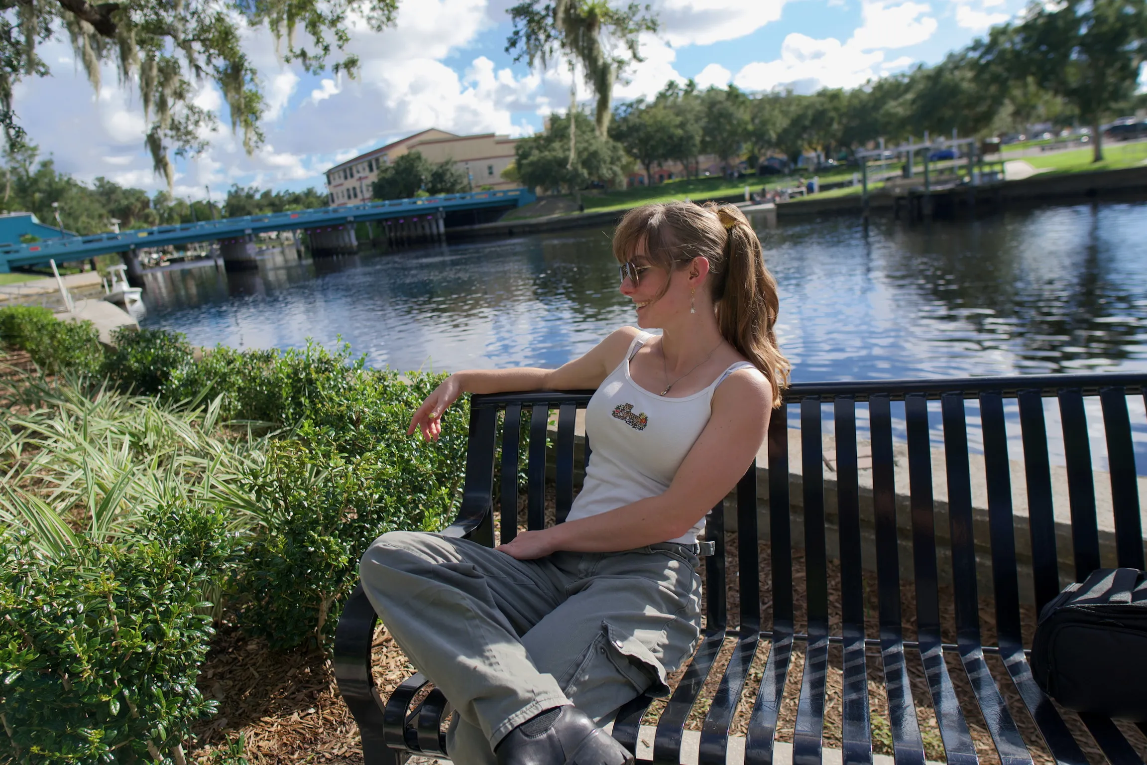 A woman on a waterside bench looking toward the marina